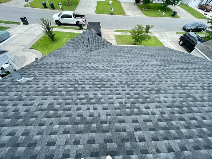 Aerial view of a completed gray shingle roof over a residential street
